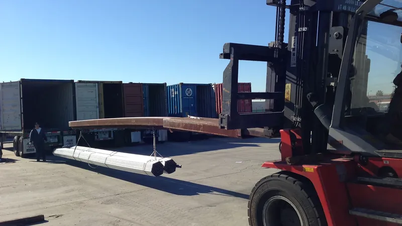 Long greenhouse tubing being trans-loaded from a shipping container